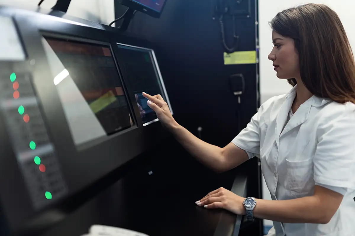 Frau in weisser Laborkleidung bedient Touchscreen
